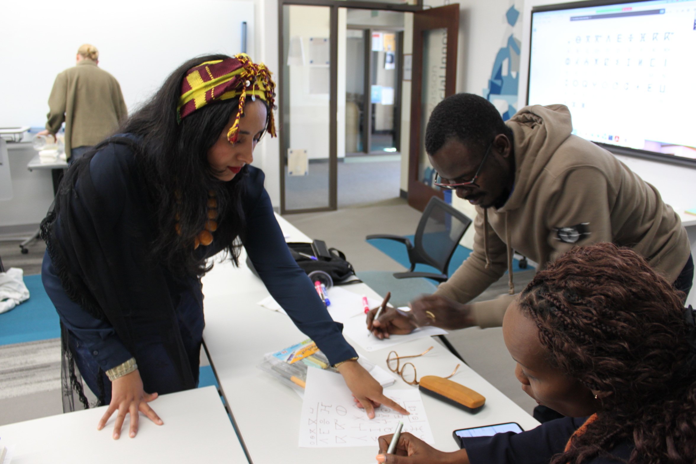 Bochra Laghssais helps Kroc School students write their names in the Tamazight language